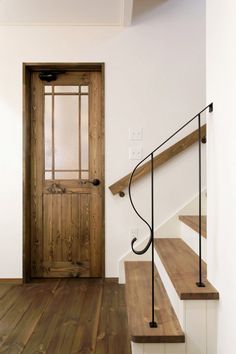 a wooden door sitting next to a set of stairs on top of a hard wood floor