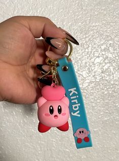 a hand holding a keychain with a pink pig on it