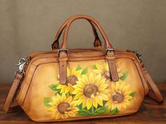 a handbag with sunflowers painted on the front and sides, sitting on a wooden table