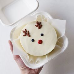 a person holding a container with a cake in it and reindeer decorations on the side