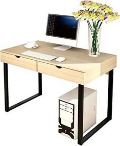 a computer desk with a monitor, keyboard and mouse on it next to a flower vase