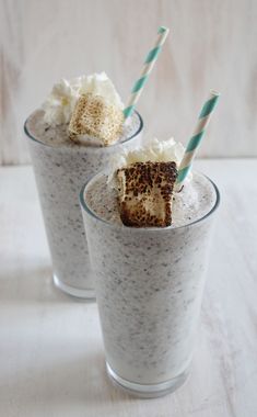 two glasses filled with pudding and ice cream on top of a white table next to each other