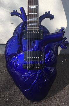 a blue heart shaped guitar sitting on the ground