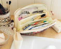 an open purse sitting on top of a wooden table next to a cup and brush