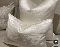 two white pillows sitting next to each other on a bed