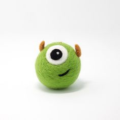 a green ball with eyes and horns on it's head, sitting in front of a white background