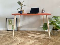 a laptop computer sitting on top of a wooden table next to a potted plant