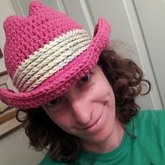 a woman with curly hair wearing a pink hat