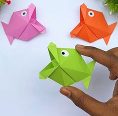 origami fish with eyes and nose displayed in front of other paper decorations on white surface