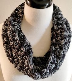 a gray and black crocheted scarf on a mannequin