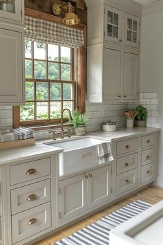 a large kitchen with white cabinets and wooden floors is pictured in this image, there are two windows above the sink