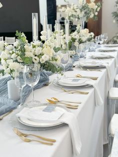 the table is set with white flowers and silverware for an elegant dinnereonal