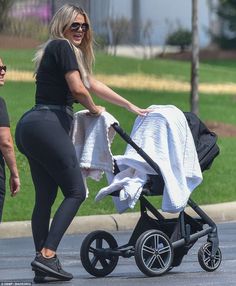 a woman pushing a stroller with a baby in it