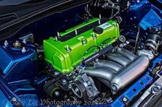 the engine compartment of a blue car with an electric green block on it's hood