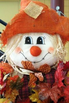 a stuffed snowman wearing a red hat and scarf with autumn leaves around it's neck