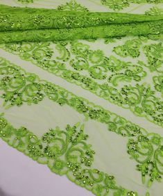 green lace with sequins and beads on a white table cloth, closeup