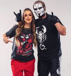 a man and woman with painted faces pose for a photo while wearing wrestling gear in front of a white background