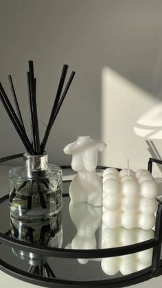 a glass table topped with candles next to a vase filled with liquid and reeds