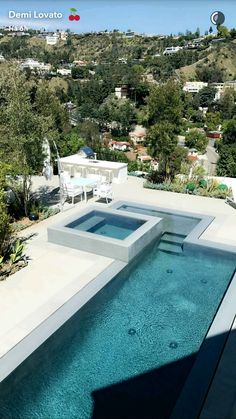 an aerial view of a swimming pool and patio area with trees in the back ground