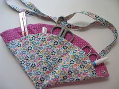 a pair of scissors sitting on top of a pink flowered bag with white handles