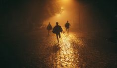 three people walking down a street at night