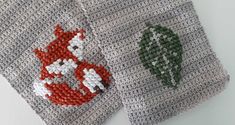 two crocheted coasters with red fox and green leaves on them, one is gray and the other is white