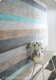 a vase with flowers sitting on top of a table next to a wall made out of wood planks