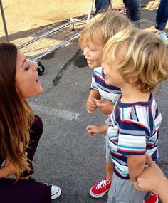 a woman is talking to two small children