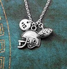 a football and helmet necklace on a green shirt with the word's in silver