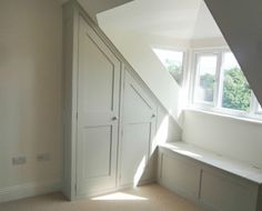 an attic bedroom with white walls and built - in storage