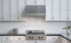 a stove top oven sitting inside of a kitchen next to white cabinets and counter tops