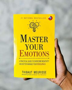 a person holding up a yellow book with the title'master your emotionss '