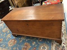 an old wooden chest sitting on top of a blue rug in front of a dresser