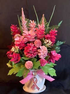 a white vase filled with pink and red flowers