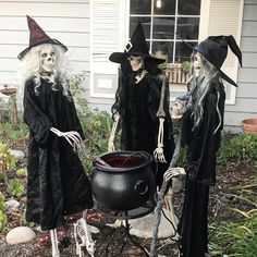 three halloween witches standing in front of a house with a caulder full of liquid