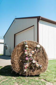 a hay bale with flowers on it in front of a building