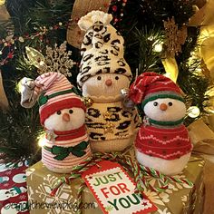 three knitted snowmen sitting next to each other on top of a christmas tree