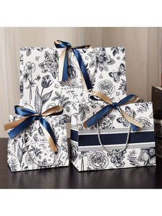 three gift bags with blue ribbons tied around them on top of a table next to books