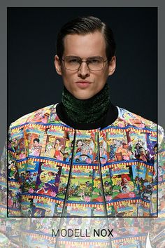 a man wearing glasses and a colorful shirt with pictures on the sleeves is shown in front of a black background