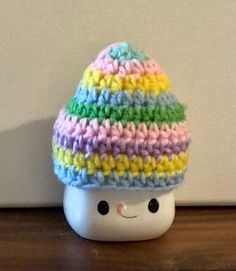 a small crocheted hat sitting on top of a wooden table next to a white wall