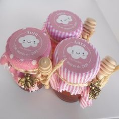 three pink cupcakes sitting on top of each other next to a honey jar