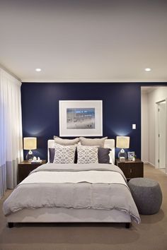 a bedroom with blue walls and white bedding in the center, along with two lamps on either side of the bed