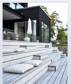 some pillows are sitting on the steps to a black and white house with an umbrella