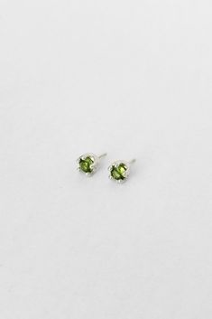 two small green gems are on top of each other in the shape of heart earrings