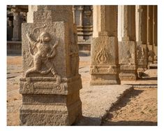 some very pretty stone sculptures in the middle of a dirt field with other statues behind them