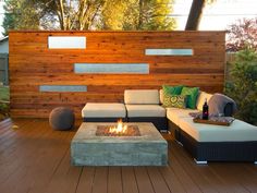 a fire pit sitting on top of a wooden deck next to a wall covered in wood planks