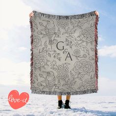 a woman is holding up a blanket with the letters c and a on it in the snow