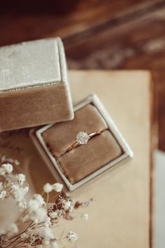 an engagement ring sits in a box next to flowers