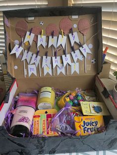 an open box filled with lots of different items on top of a table next to a window