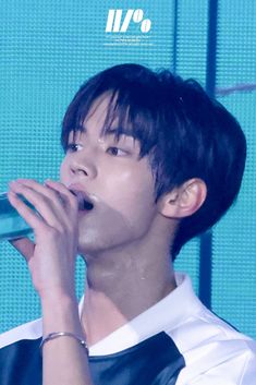 a young man holding a microphone up to his mouth while wearing a white shirt and black vest